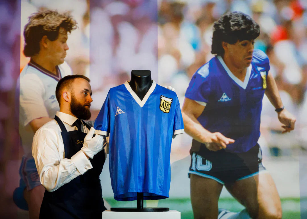 Man showcasing Maradonna's football jersey in an auction